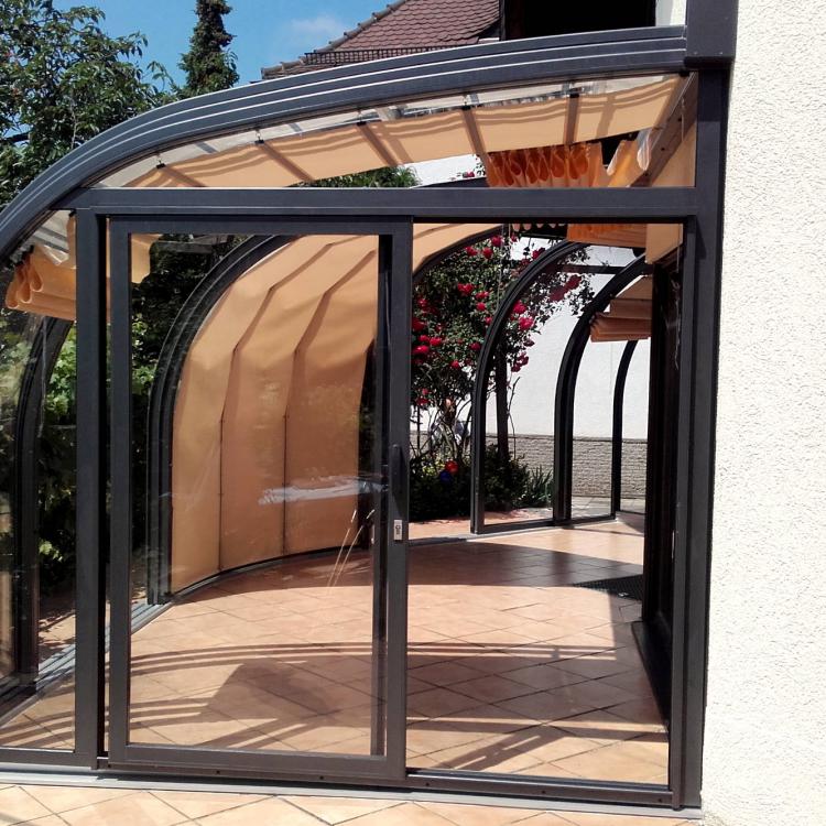 Abri de terrasse qui suit l'angle extérieur de la maison avec un quart de rotonde
										